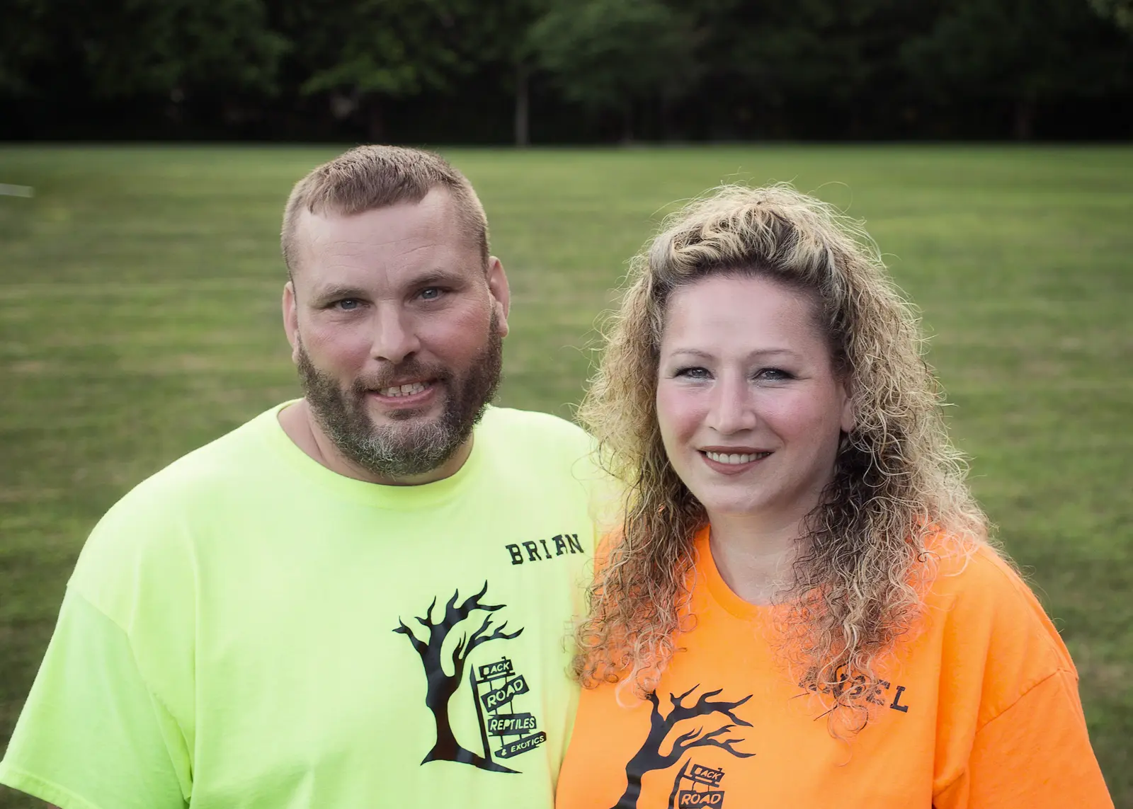 Brian and Angel, owners of Back Road Reptiles and Exotics, outdoors in branded shirts